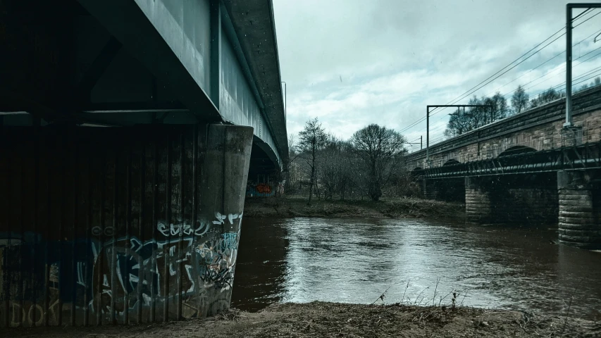 water on the side of a road under a bridge