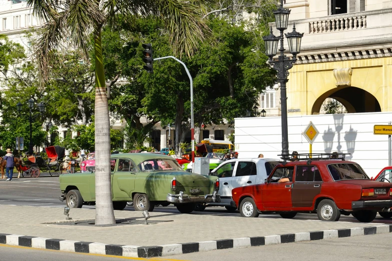 some old cars parked next to a tree in a city