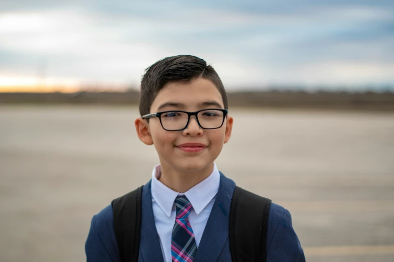 a  in glasses wearing a blue vest and tie