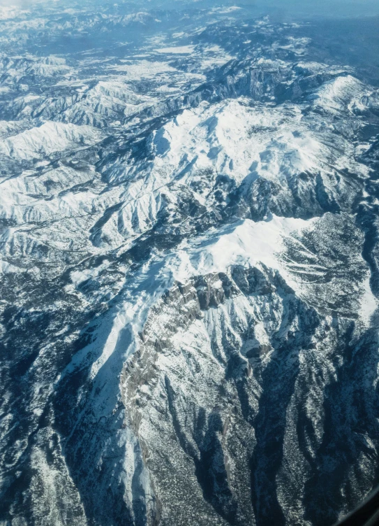 an airplane wing showing a snow covered mountain range