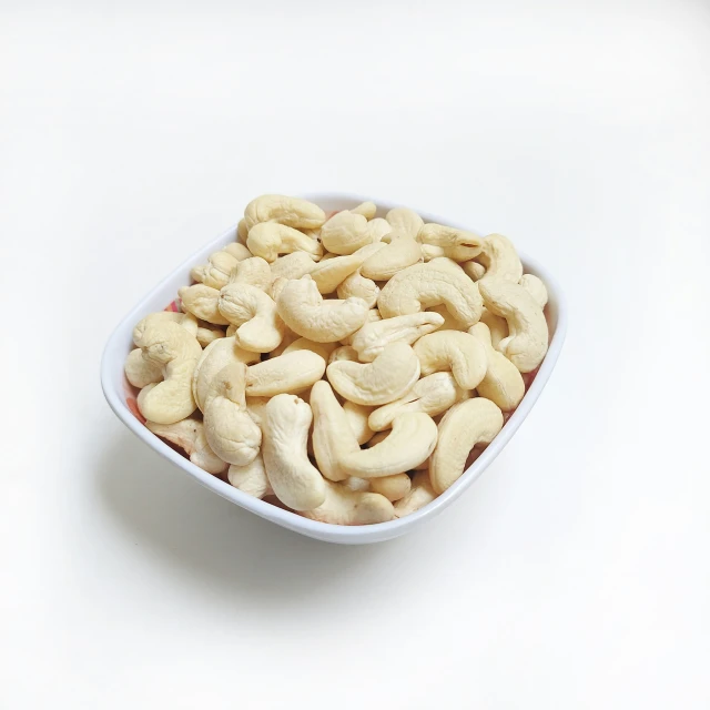 a close up of a small white bowl of cashews