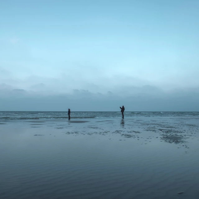 two people stand in the surf on an empty beach