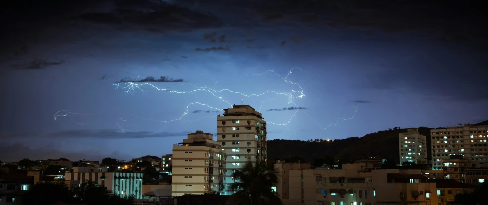 lightning strikes through a city sky during the night