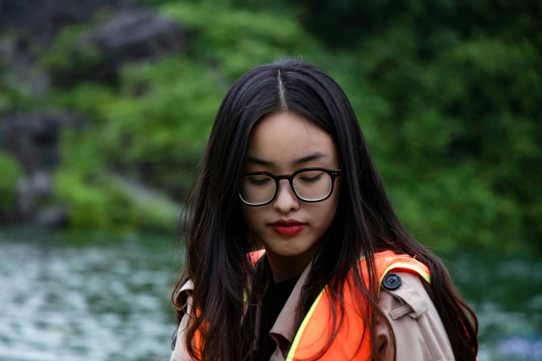 a woman with glasses wearing a safety vest next to water