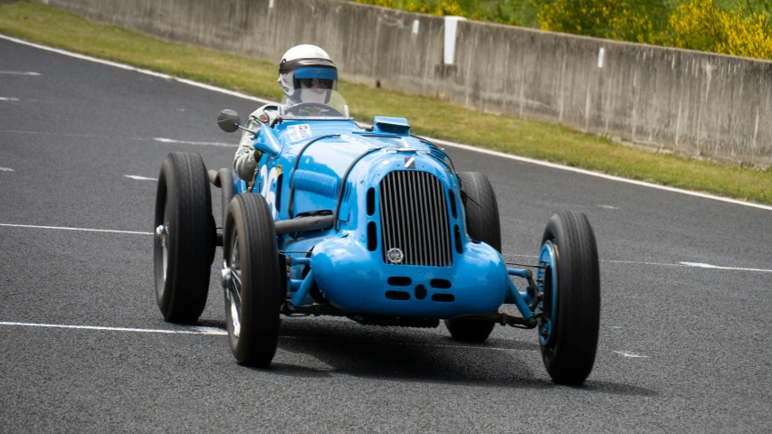 an old fashion race car races on asphalt