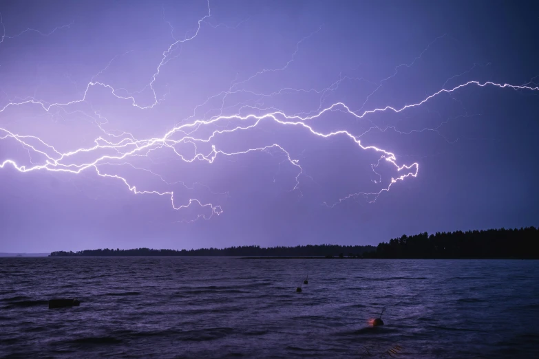 lightning strikes over the ocean with dark purple skies