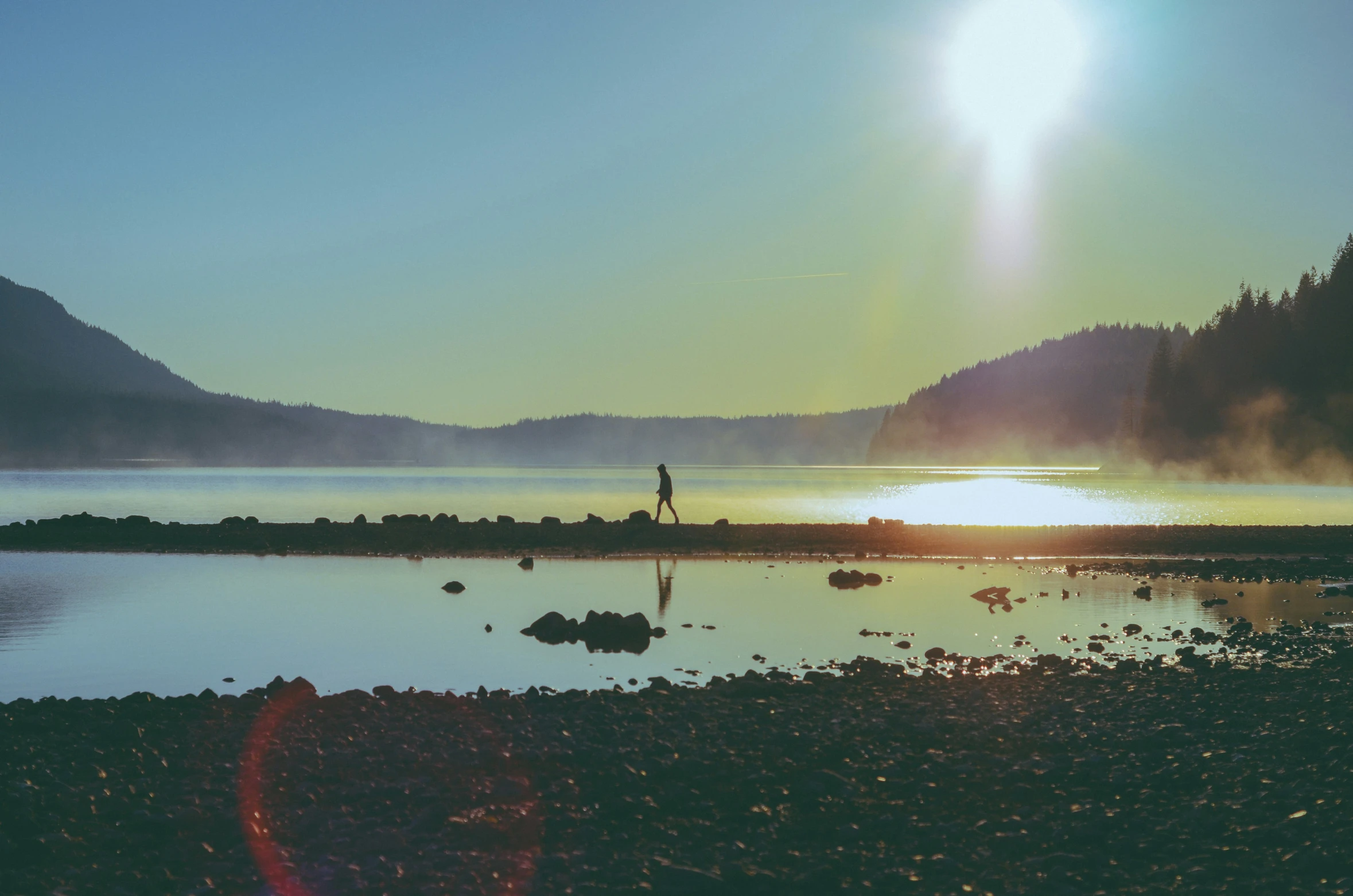 a man standing on top of a sandy beach next to water