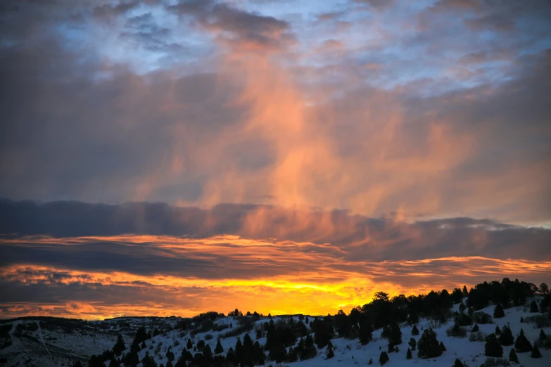 the sun is setting over a mountain range in winter