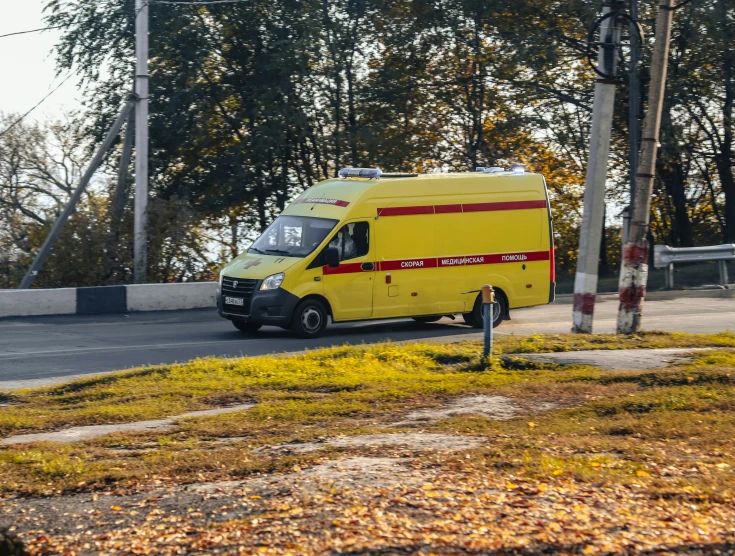 an yellow van driving on the road in front of trees