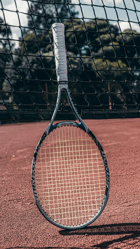 a tennis racket is on the court behind a net