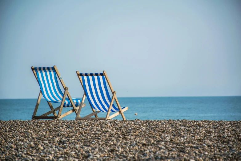 two lawn chairs sitting on top of a pebble beach