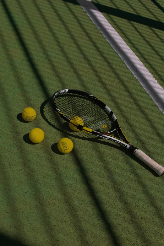 there is some tennis balls and a racket sitting on the ground