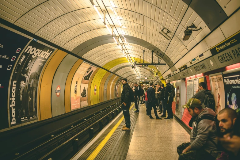 a group of people are standing on a platform by a subway