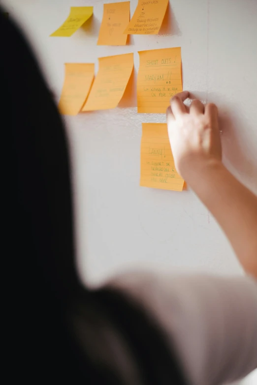 a woman points to a sticky note on the wall