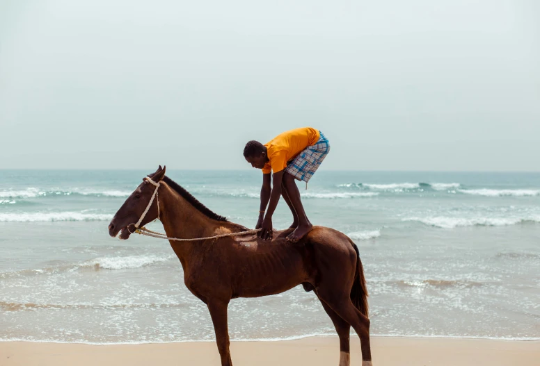 a person with a hat and yellow shirt sitting on a horse