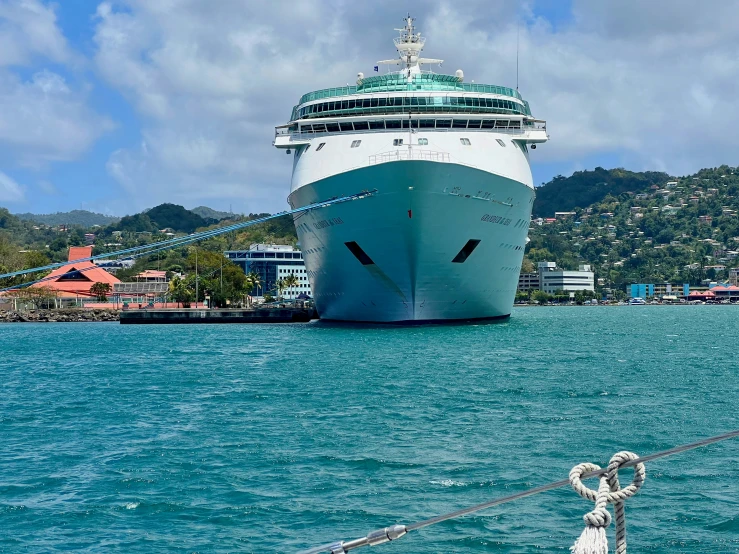 the cruise ship is in the water and is tied to a post