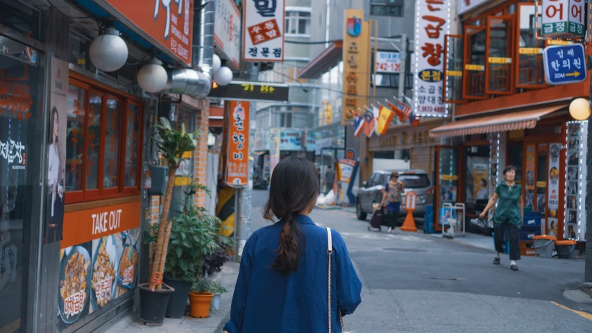 a woman is walking along the street by buildings