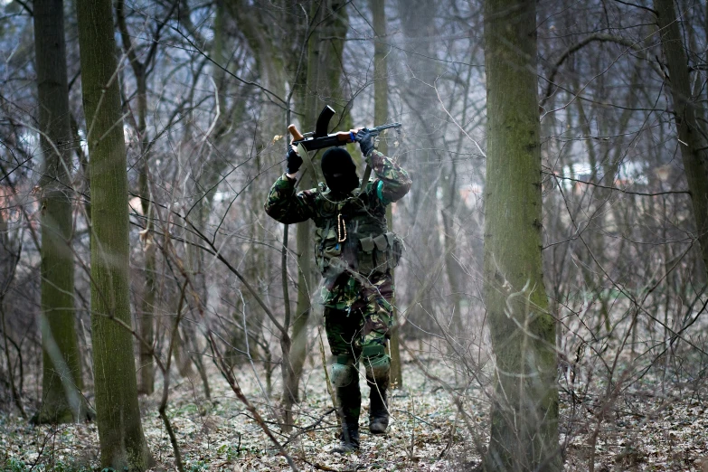 a soldier carrying two guns in a forest