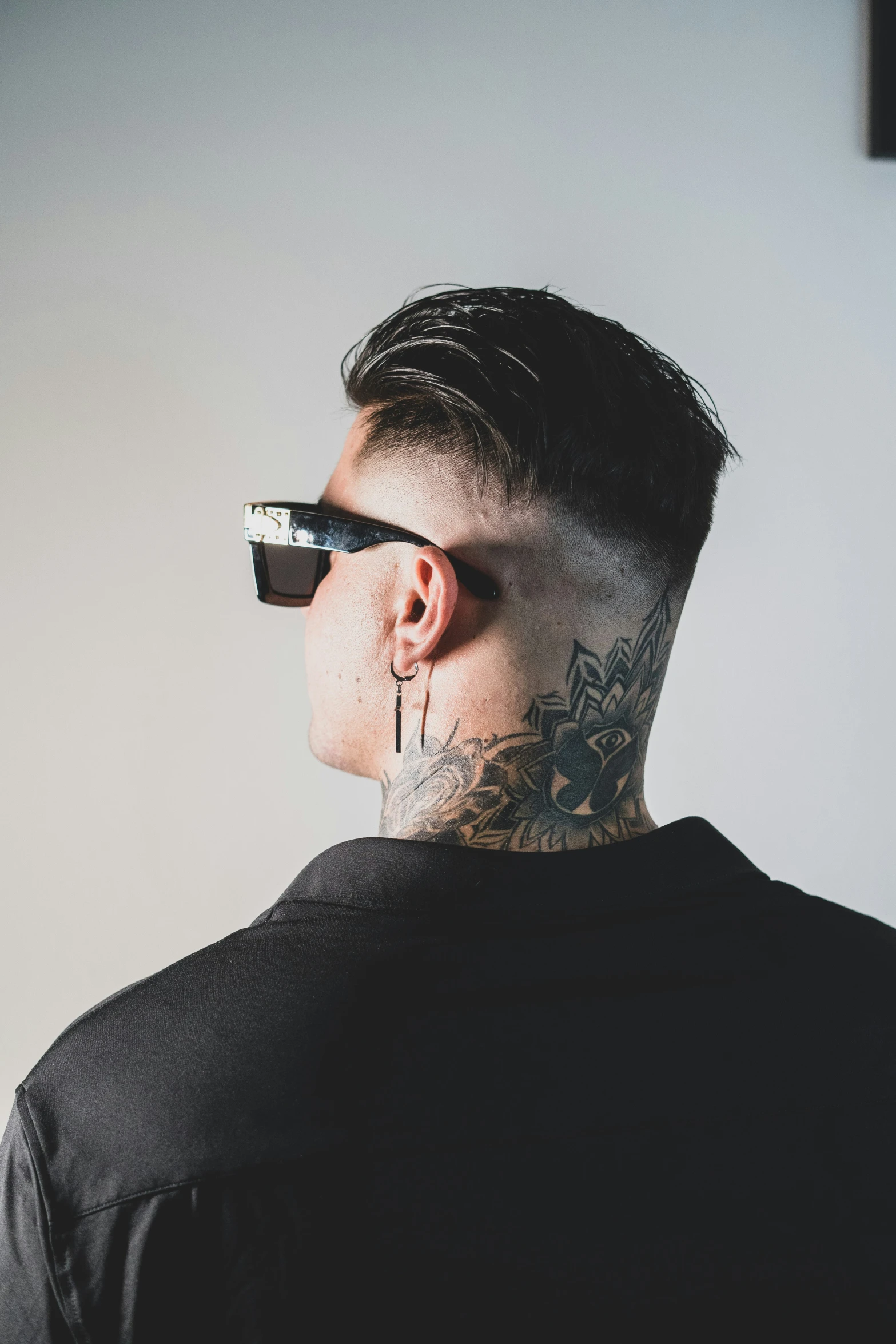 a man with tattoo on his neck looking down