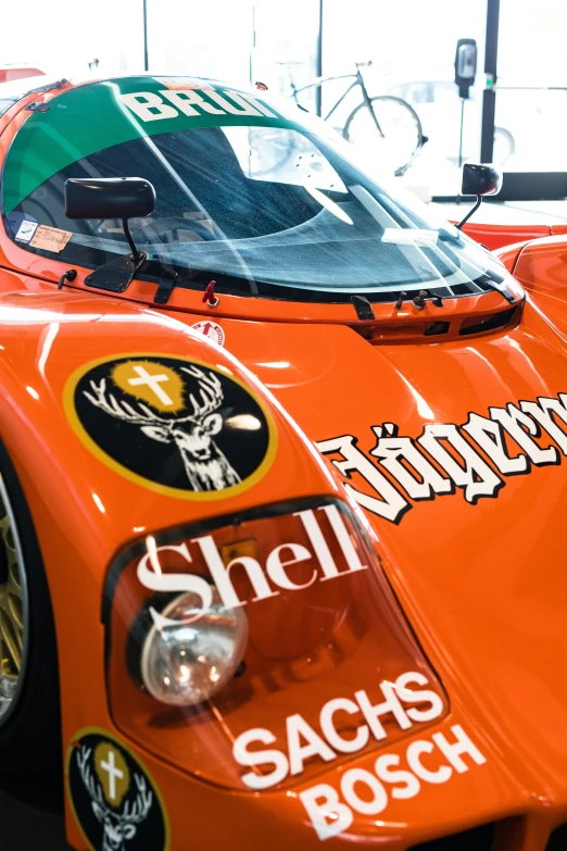 an orange racing car with various logos on the front and side