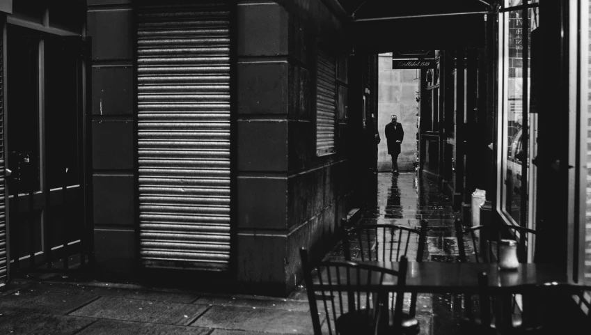 black and white pograph of a man walking through a doorway between two tables