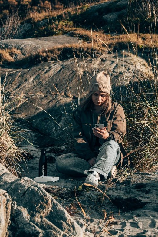 woman sitting on rocks using a cell phone