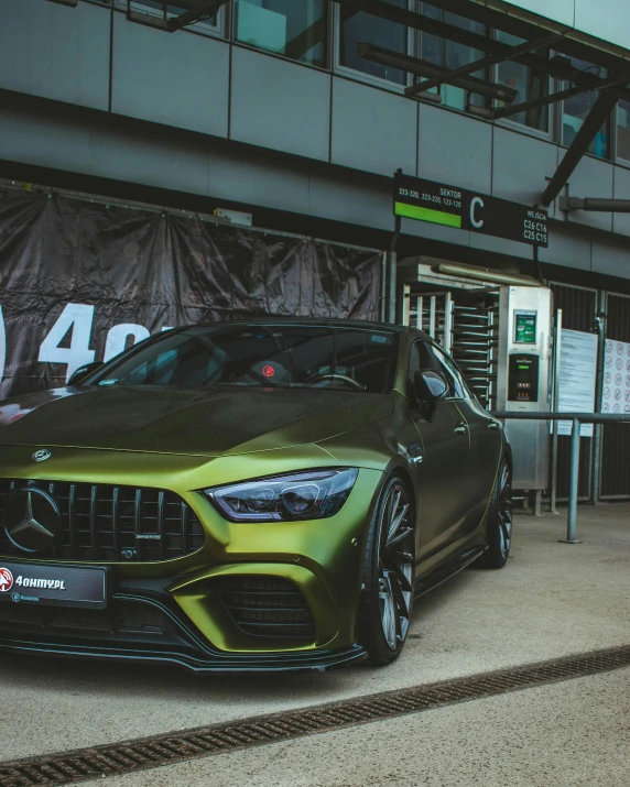 a green mercedes cla parked in front of a gas station