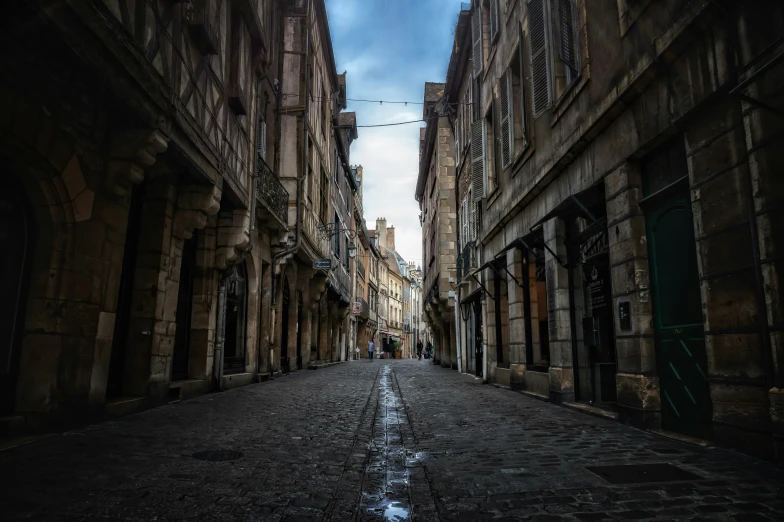 a narrow alley with cobblestone stones, a pedestrian walking past it