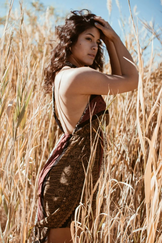 woman in brown dress in grass field with earphones