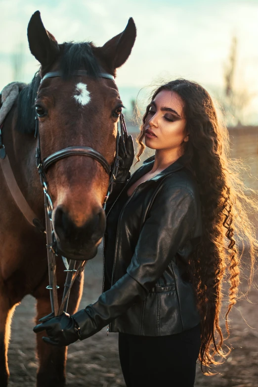 a woman in black leather jacket standing next to a horse