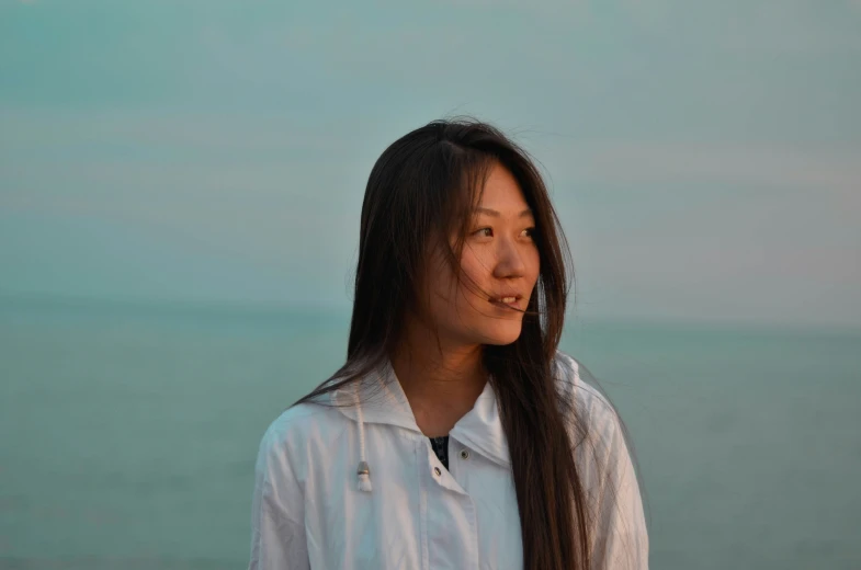 young asian woman standing on a beach with a smile