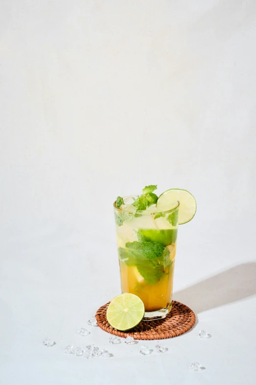 a glass with a lime and cucumber garnish sitting on a mat