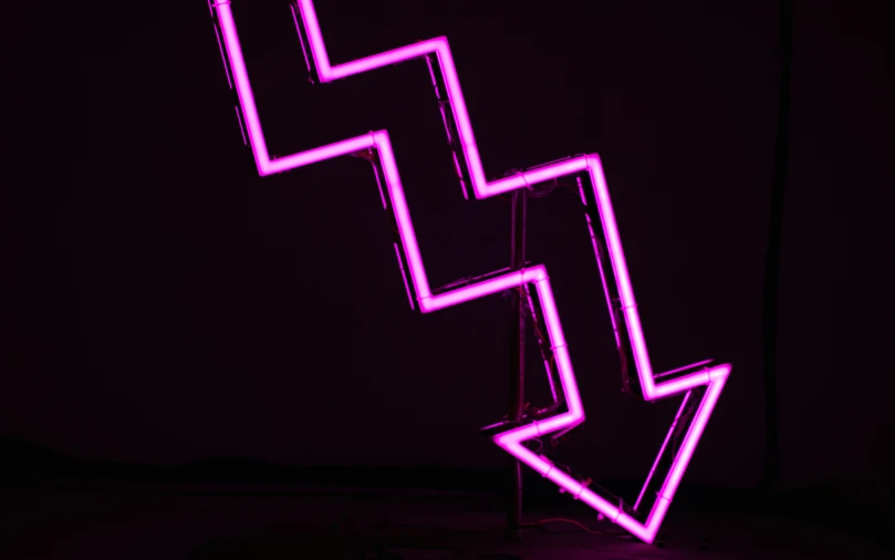 a large neon arrow in the dark