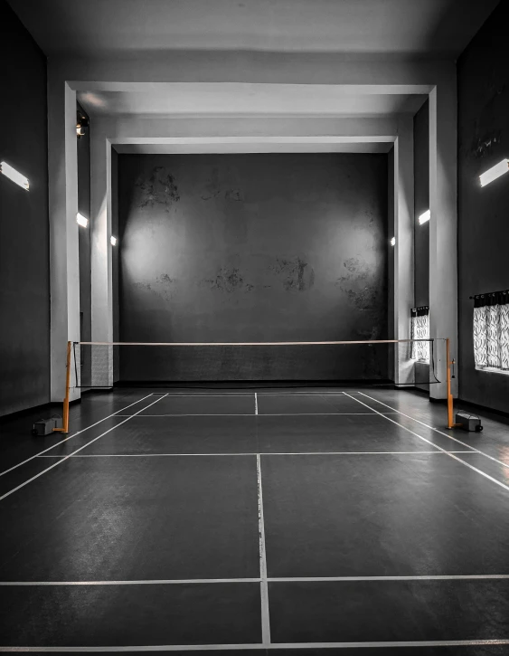 an empty indoor tennis court in the middle of the day