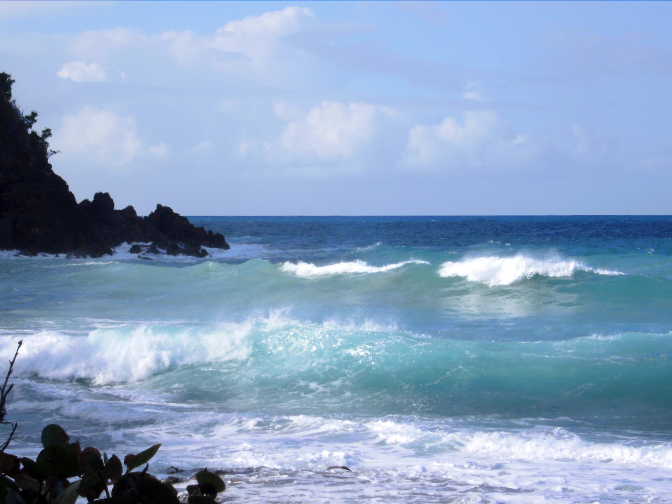 a big body of water with waves coming up from the rocks