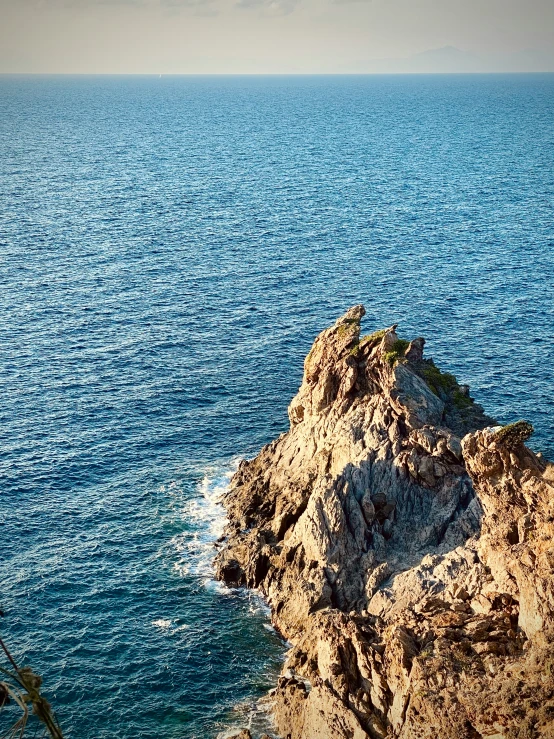 a rocky outcropping sits on the edge of the ocean