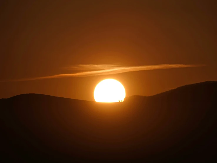 the sun is setting above the mountains with a hazy sky