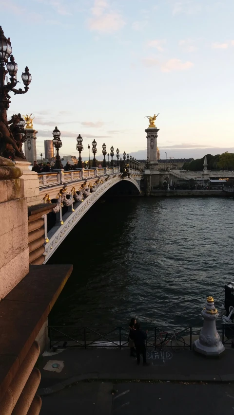 a view from the side of a bridge that has a statue and statues along it