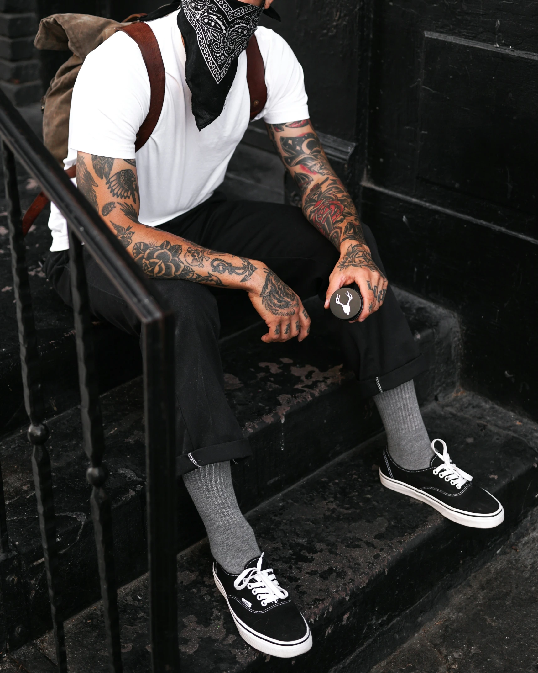 a tattooed man sitting on a stair case