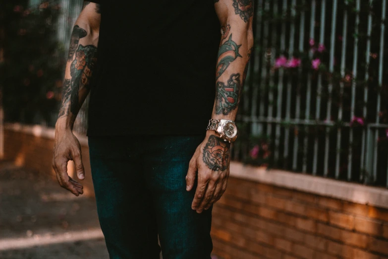 a tattooed man standing on top of a sidewalk