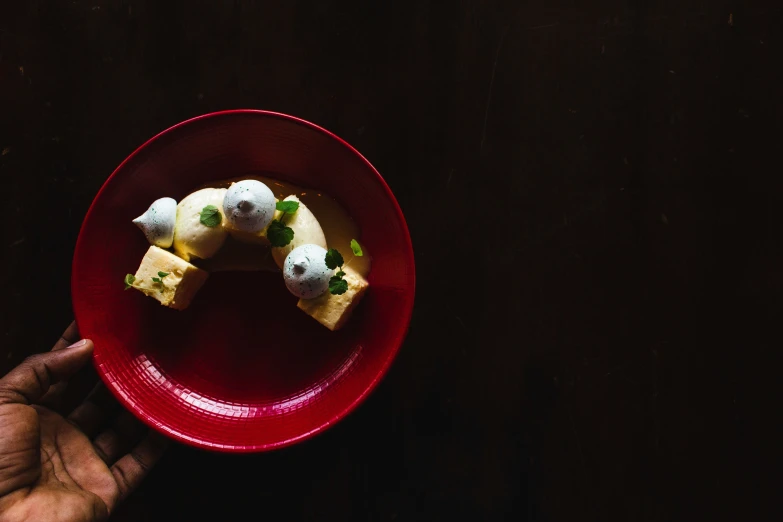 someone holding out some food on a red plate