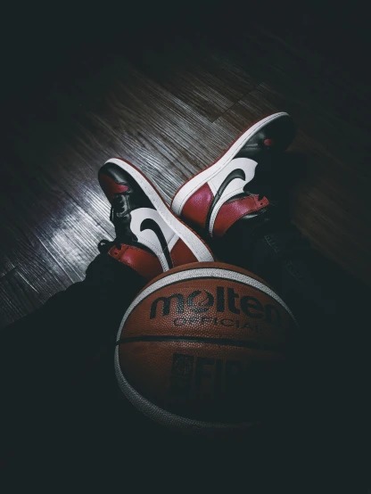 a pair of black and red shoes next to a basketball
