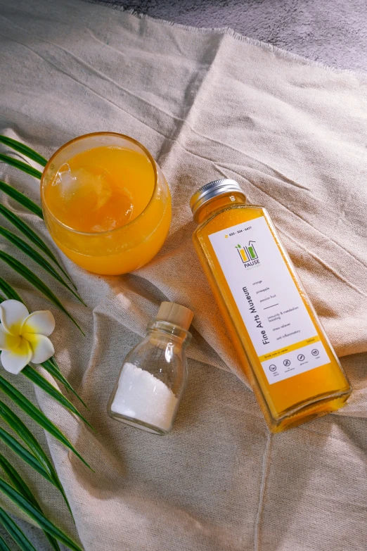 a bottle of pured lemon sits next to some jars with a small white orchid