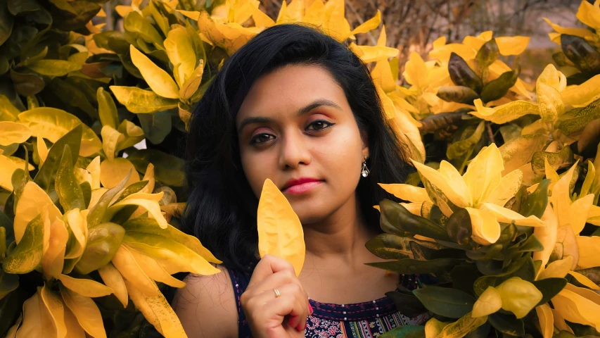 young woman surrounded by a bush of yellow flowers