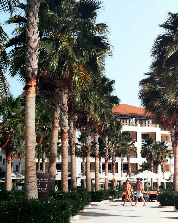 a couple is walking across the sidewalk in front of their luxurious resort