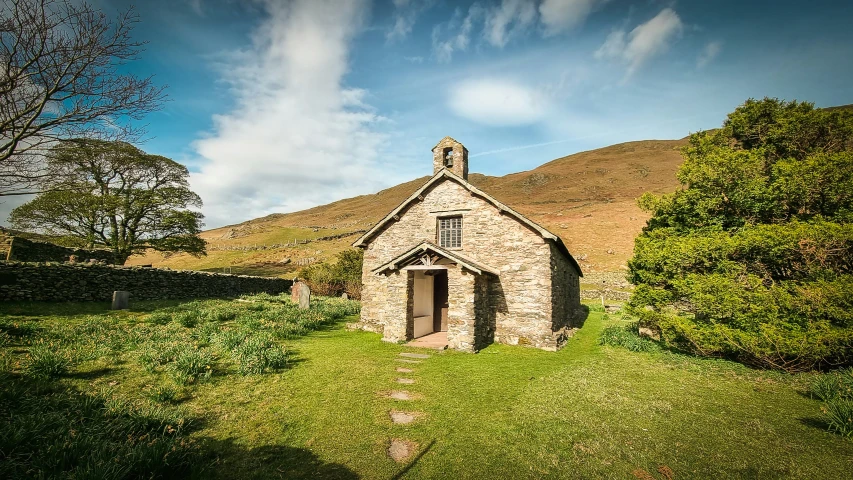 an old stone church is standing near green bushes