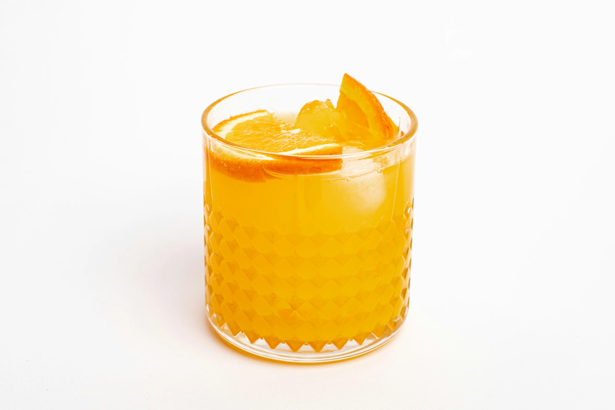 a glass of orangeade on a white table