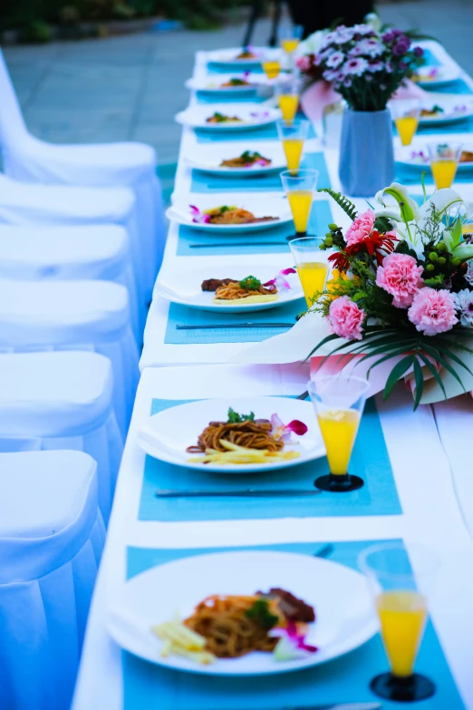 a long table filled with plates of food and flowers