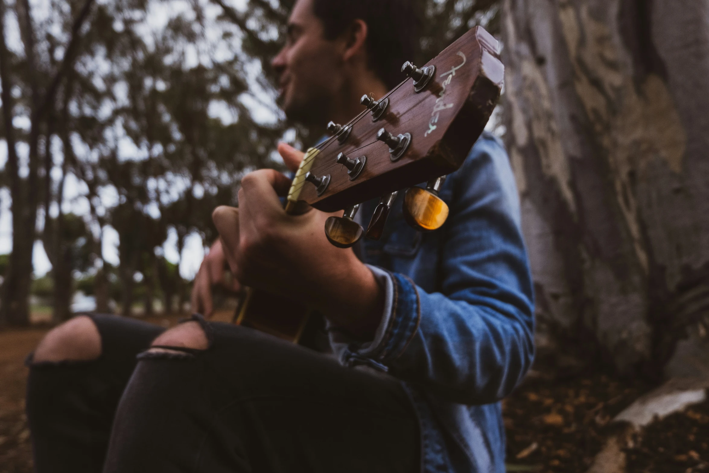 a man with a guitar neck resting on his knees