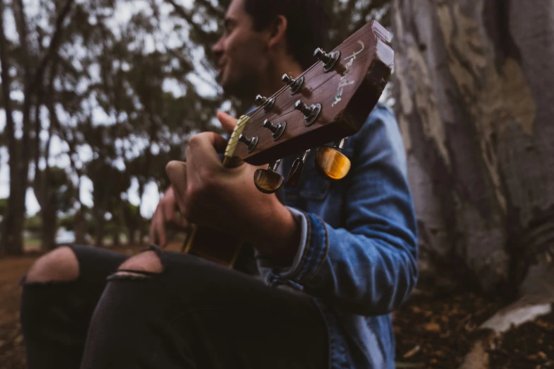 a man with a guitar neck resting on his knees